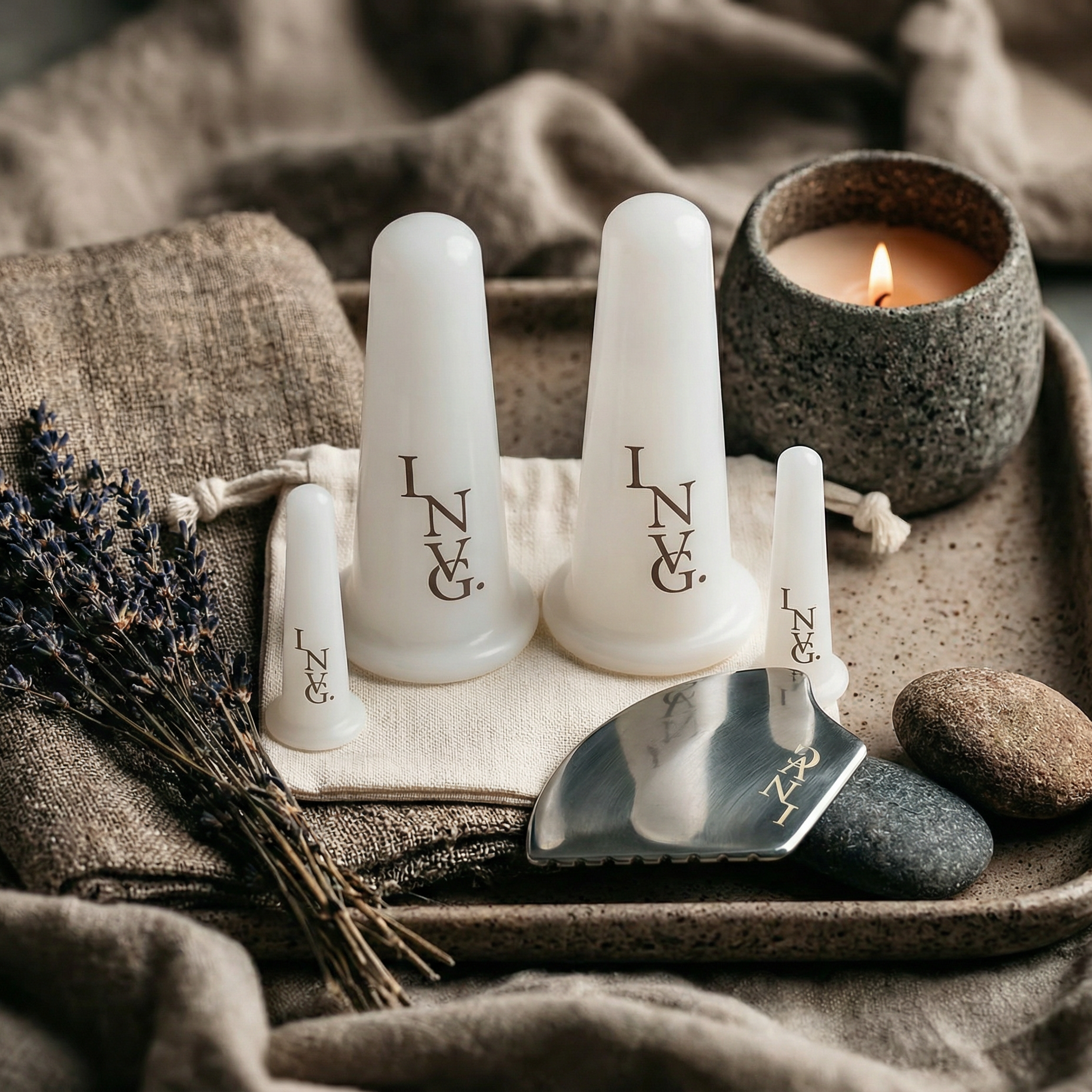 Three white ceramic containers with 'LNC' branding on a textured surface with a candle and lavender.