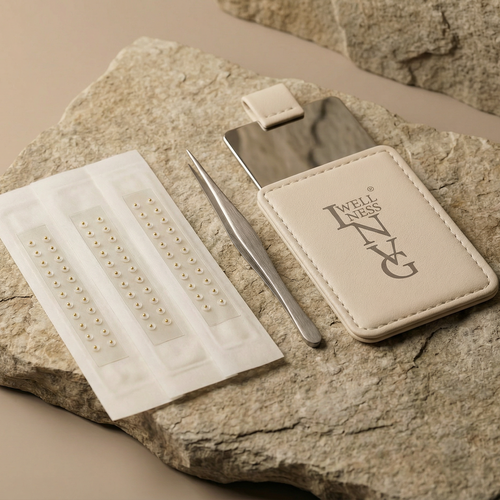 Nail art tools including a mirror, tweezers, and a tray of nails on a stone surface.