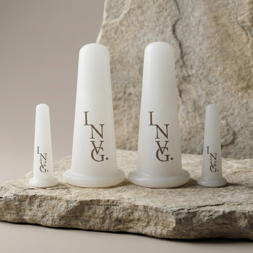Set of four white facial cups with 'INVG.' branding on a stone surface.