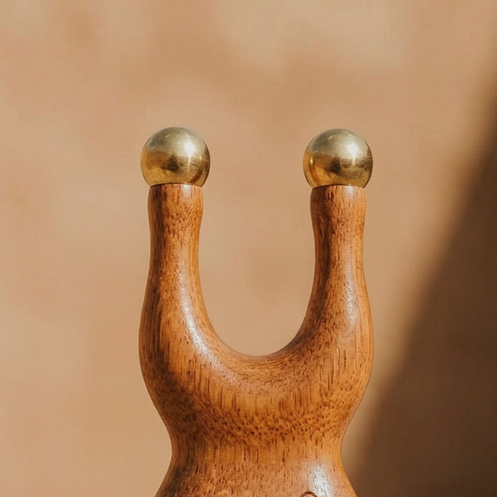 Wooden slingshot with 'Wellness NVG' branding on a sandy surface